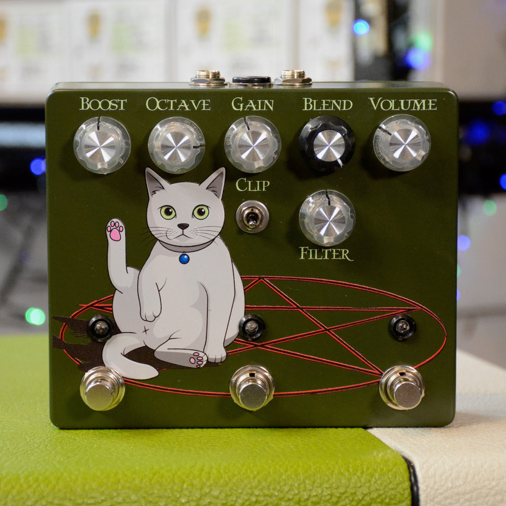 Green guitar effects pedal with cartoon cat graphic, six knobs, a toggle switch, and three footswitches on its front panel.