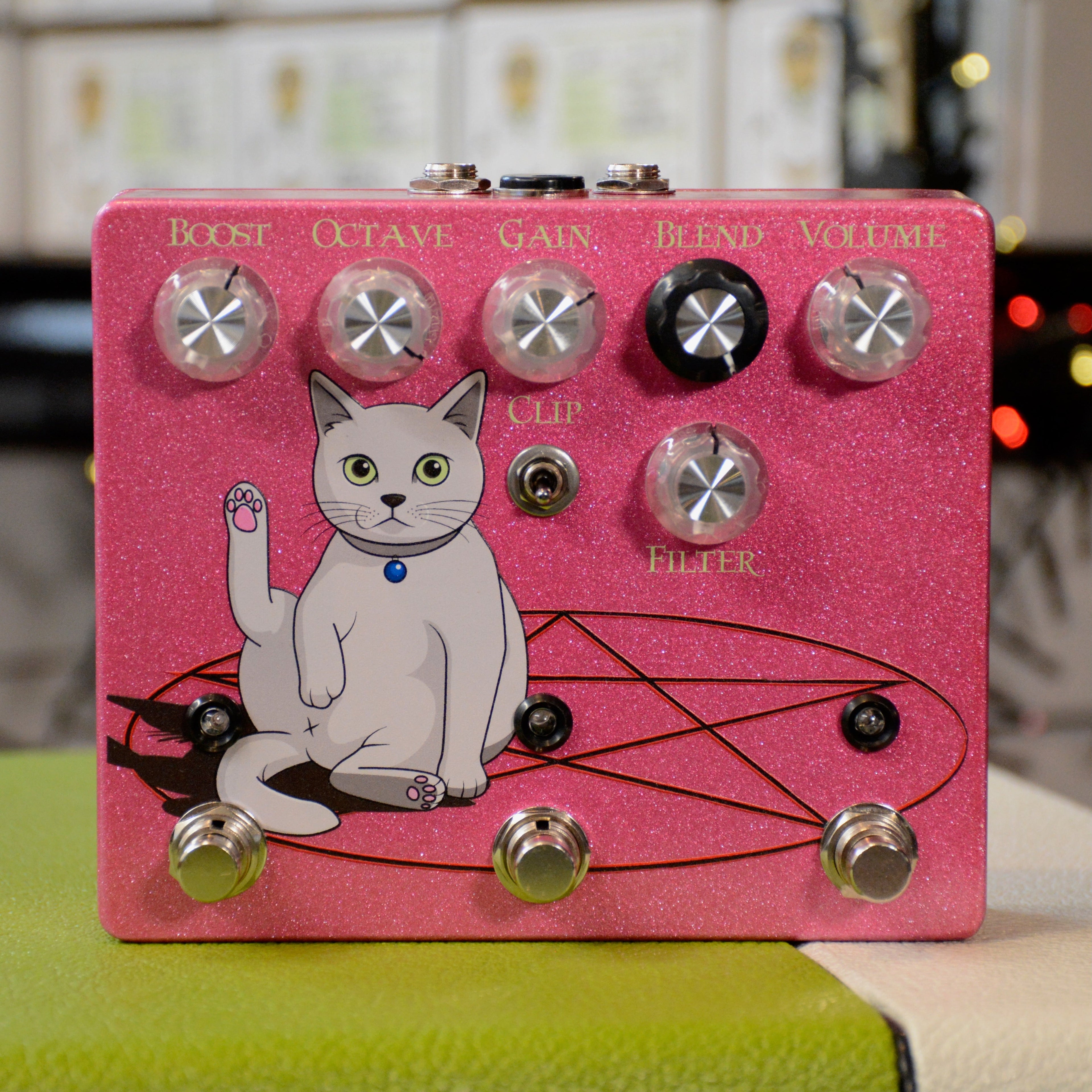 Pink guitar effects pedal with cat illustration and controls for Boost, Octave, Gain, Blend, Volume, Clip switch, and Filter.