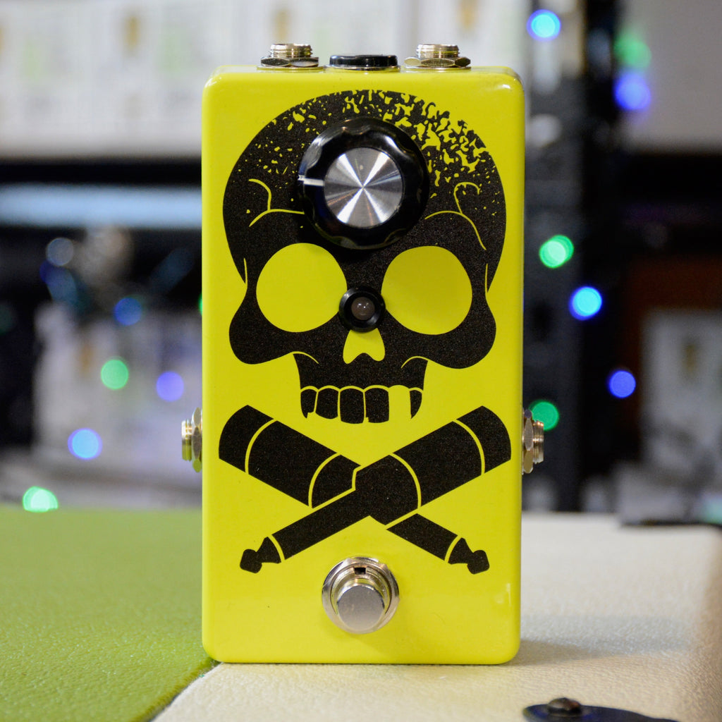 Yellow guitar effects pedal with a black skull and crossed jack plugs design, one rotary knob, and a footswitch button