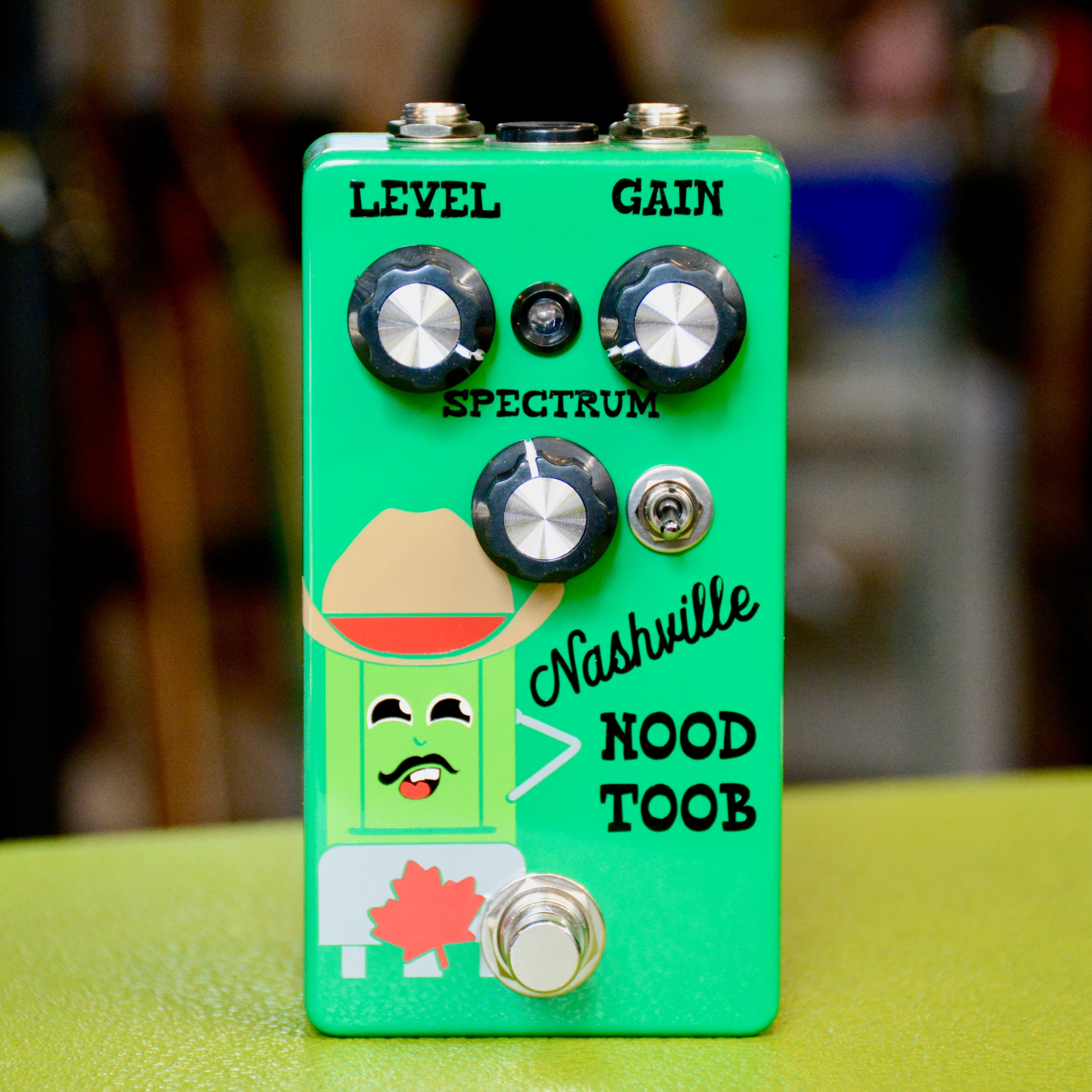 Green guitar effects pedal with three knobs, a toggle switch, and a footswitch, decorated with a cartoon character and text.