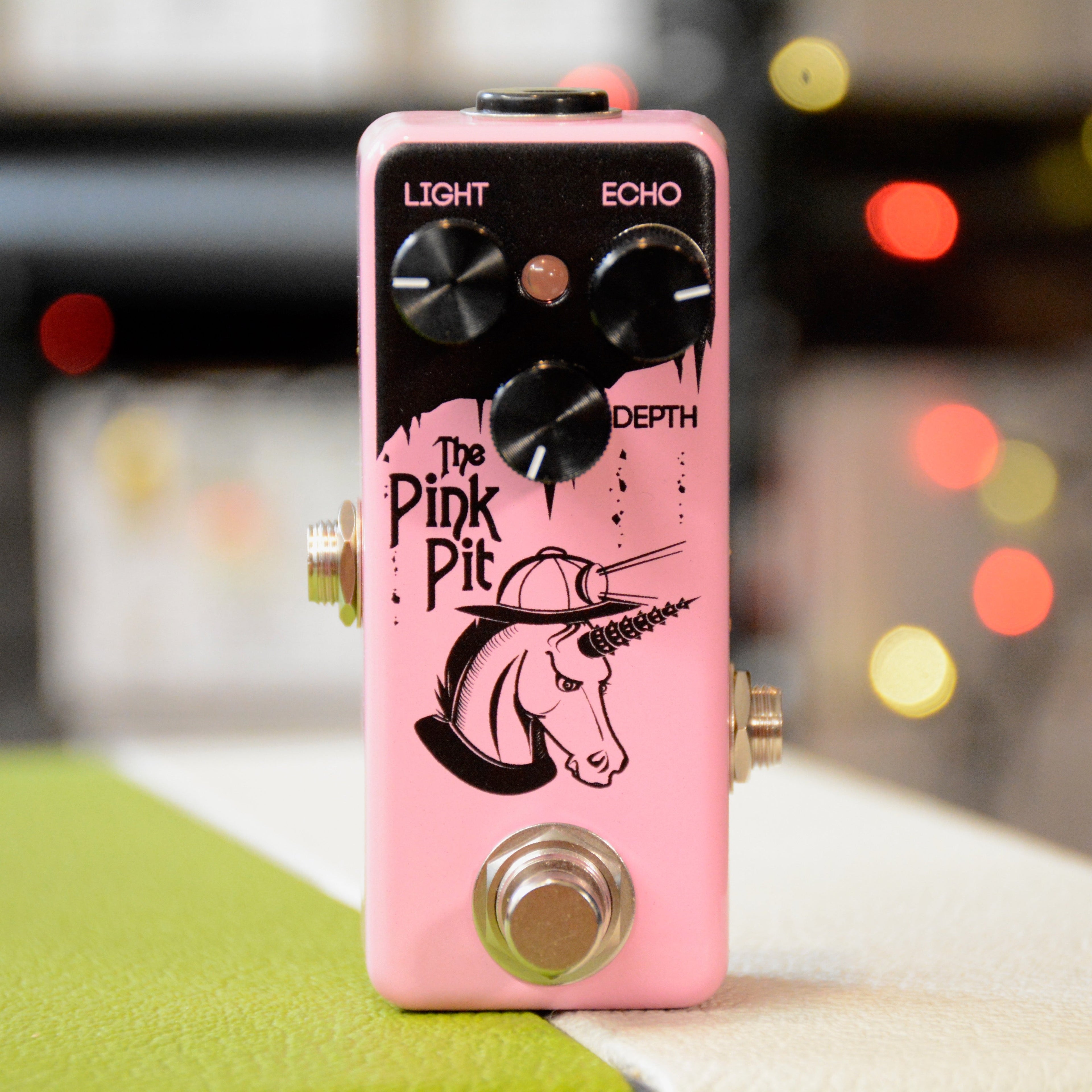 Pink guitar effects pedal with three knobs, a footswitch, and unicorn artwork on the front.