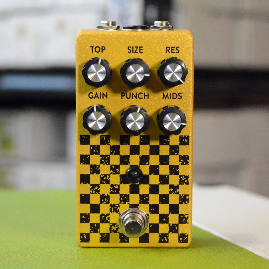 Gold and black checker patterned pedal with six knobs and a footswitch on front.