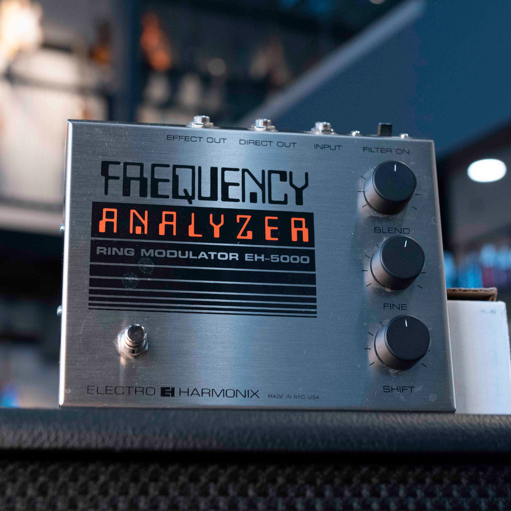 Silver metal pedal with black and orange text labeled Frequency Analyzer Ring Modulator EH-5000 with three knobs and three jacks on top
