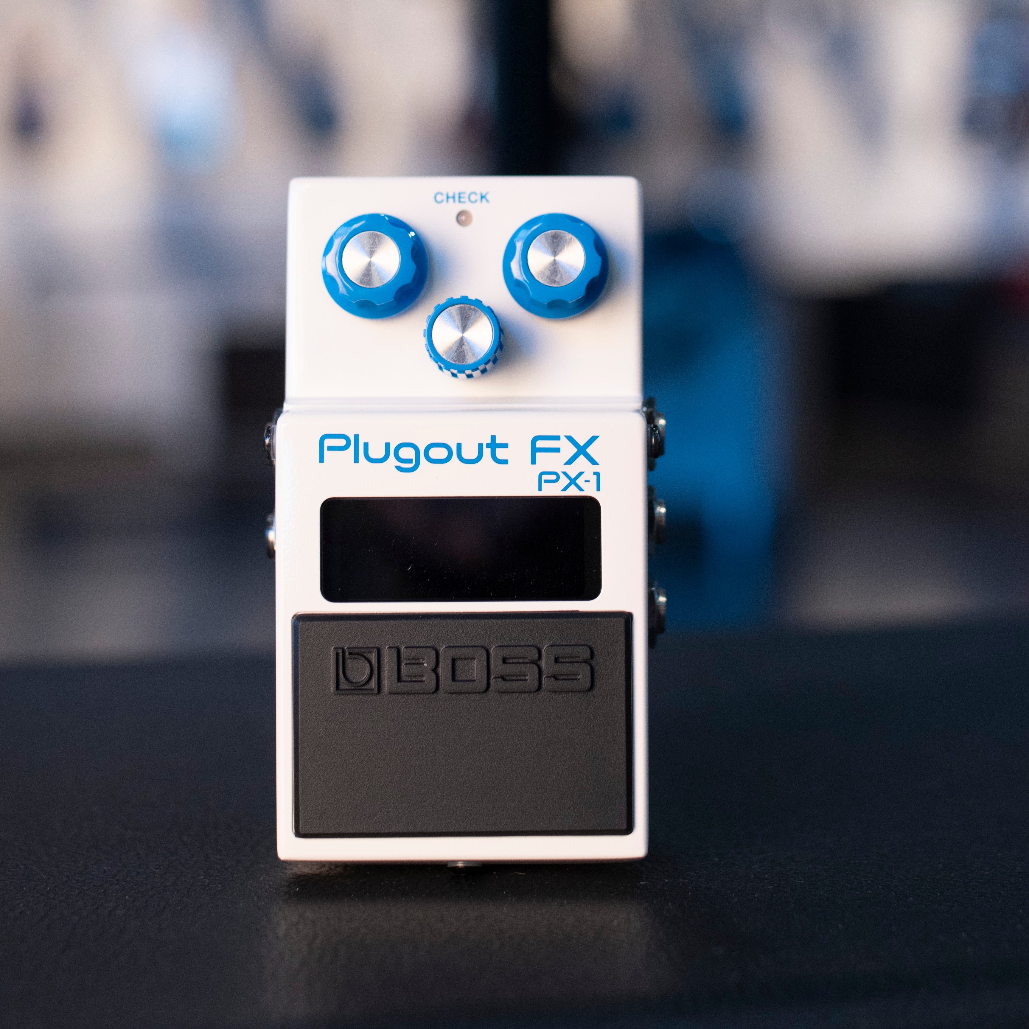 Front view of a white BOSS Plugout FX PX-1 guitar pedal with three blue knobs and a black footswitch.