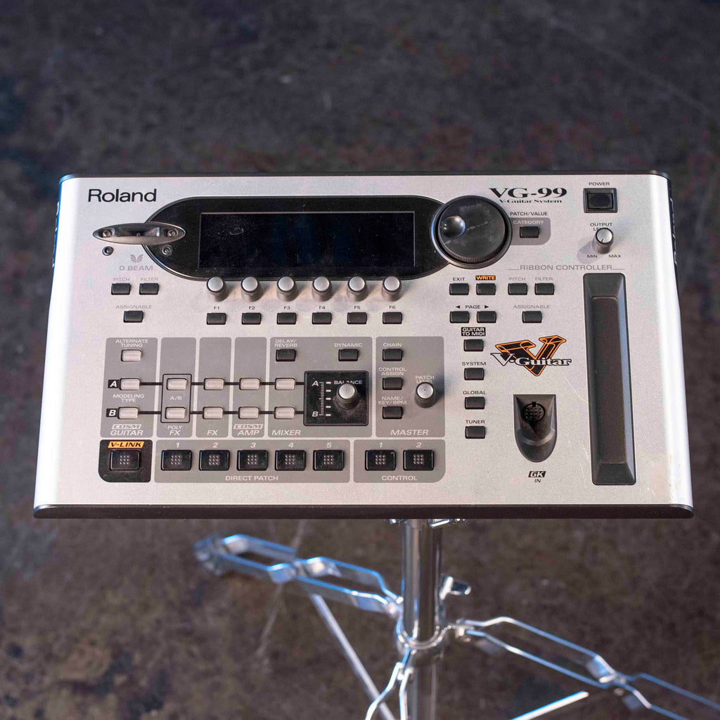 Top view of a silver Roland VG-99 multi-effects guitar processor with display, knobs, buttons, and ribbon controller.