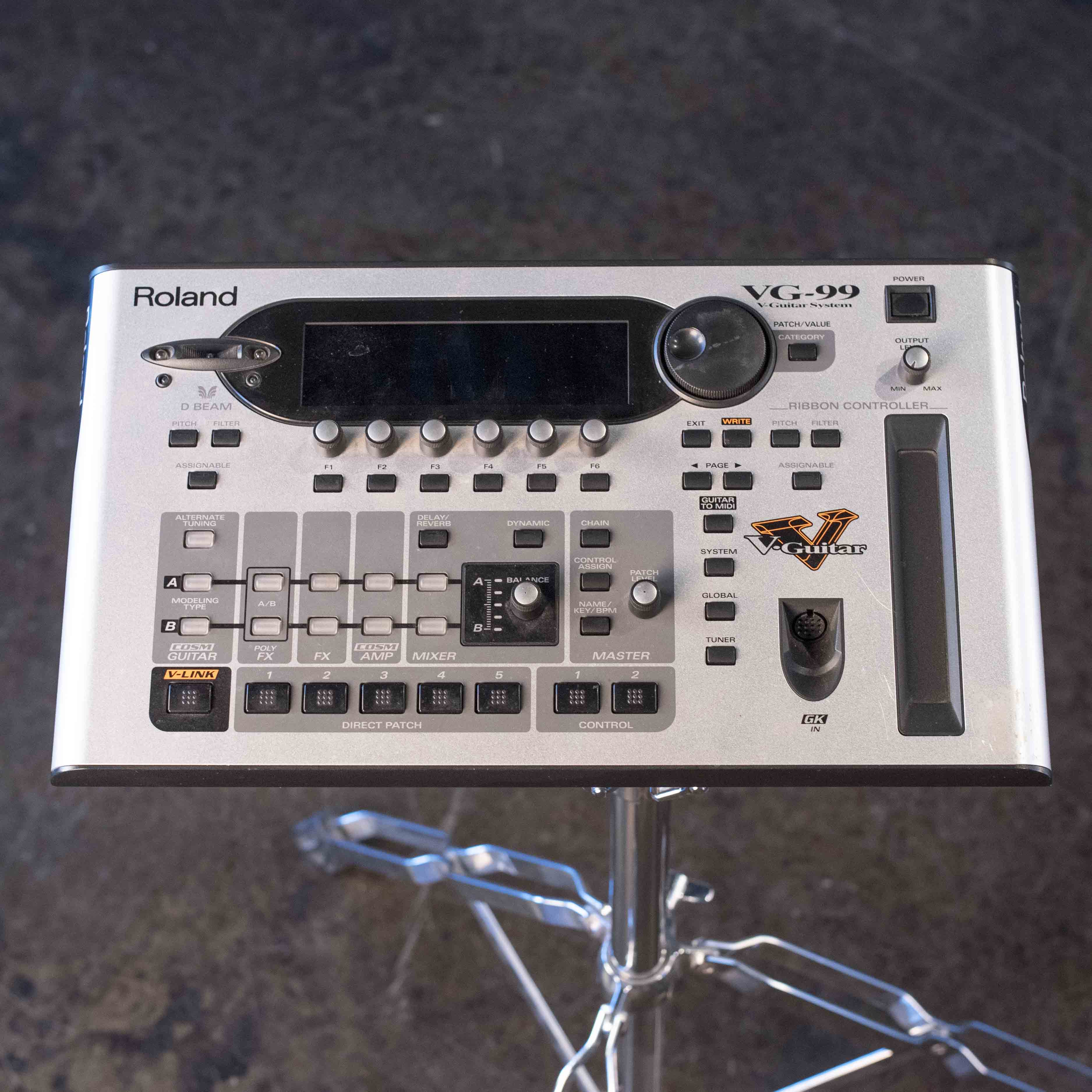Top view of a silver Roland VG-99 multi-effects guitar processor with display, knobs, buttons, and ribbon controller.