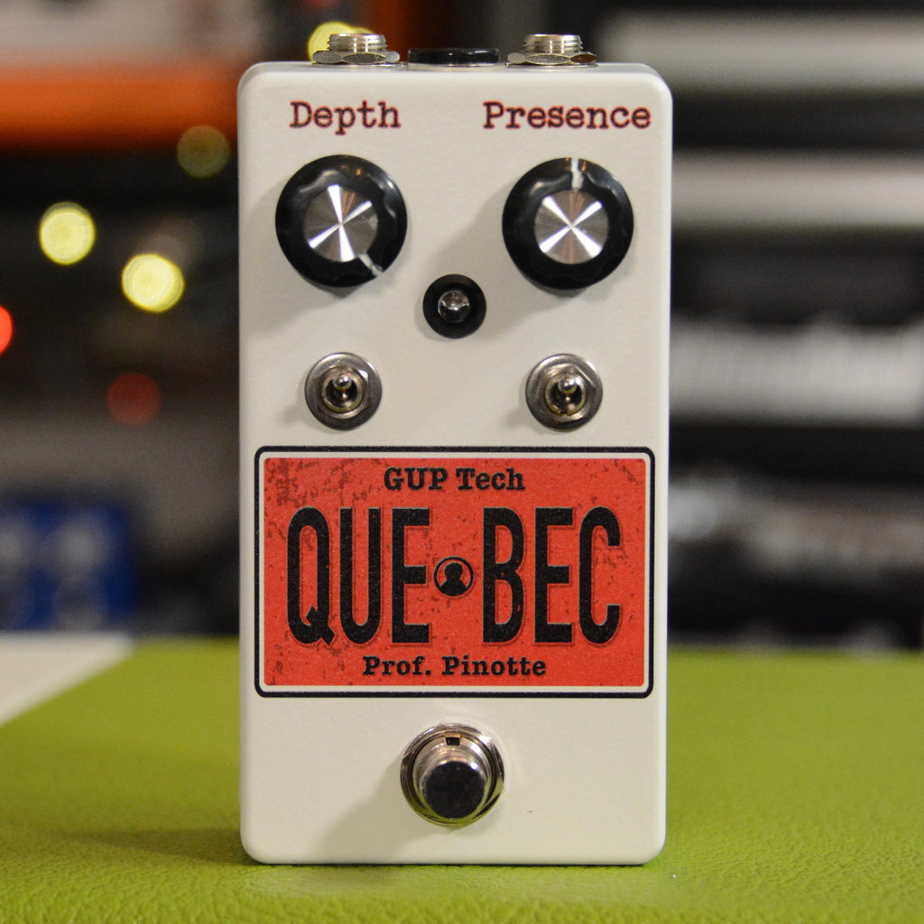 White guitar pedal with knobs labeled Depth and Presence, two toggle switches, footswitch, and red label reading QUEBEC.