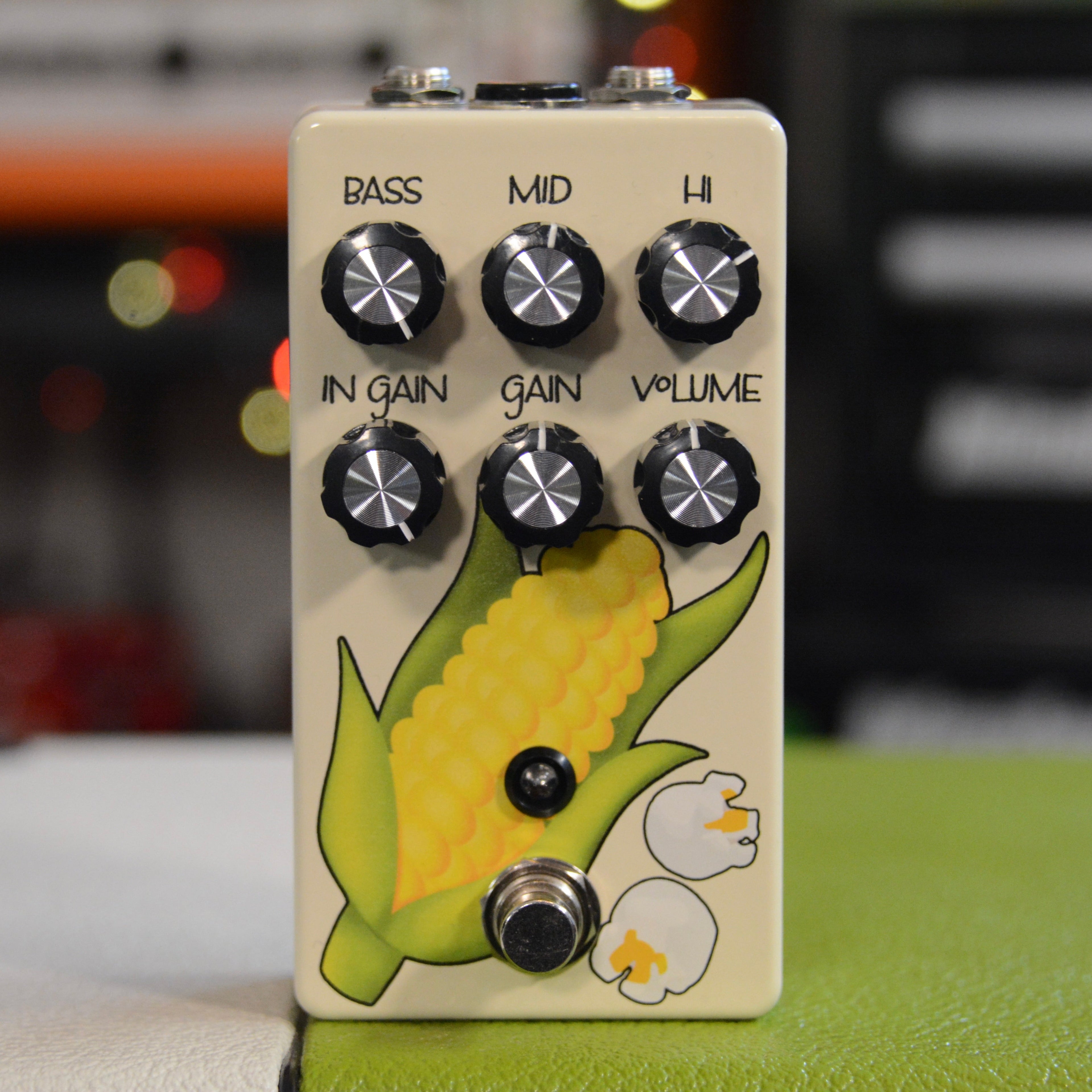 Cream colored guitar pedal with six black knobs and artwork of corn and popcorn.