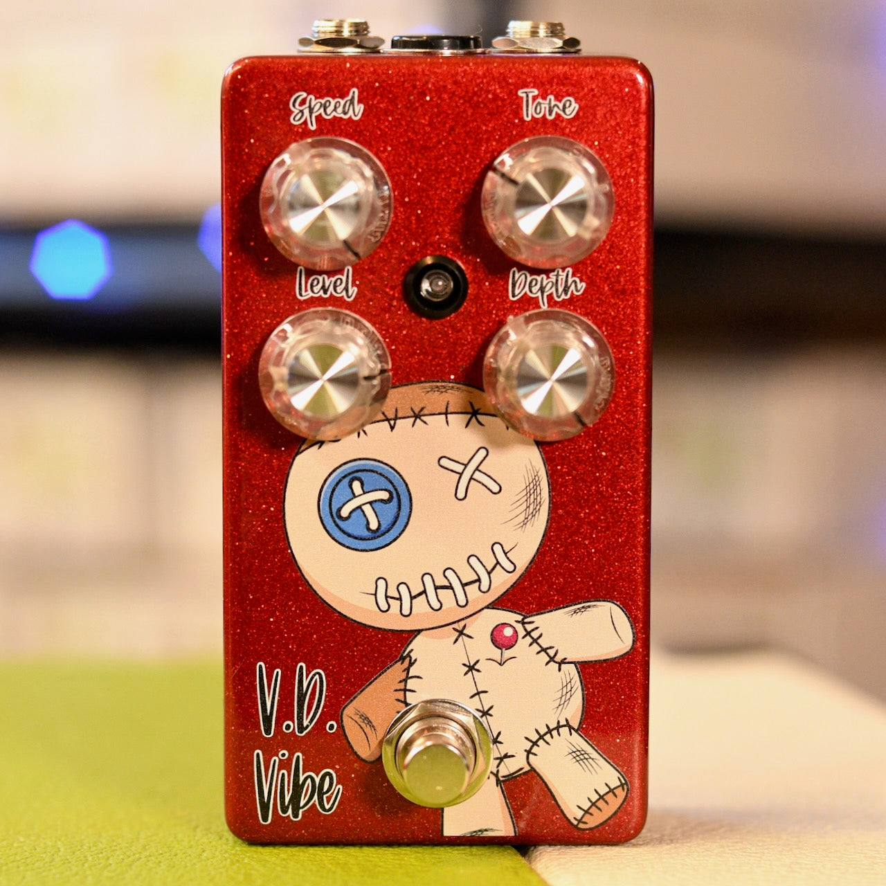 Red guitar effects pedal with four knobs, a footswitch, and voodoo doll graphic labeled V.D. Vibe.