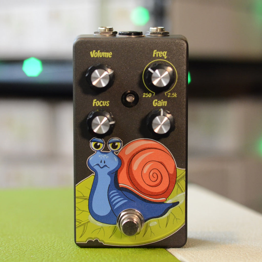 Black guitar pedal with four control knobs, a footswitch, and a cartoon snail graphic on front.