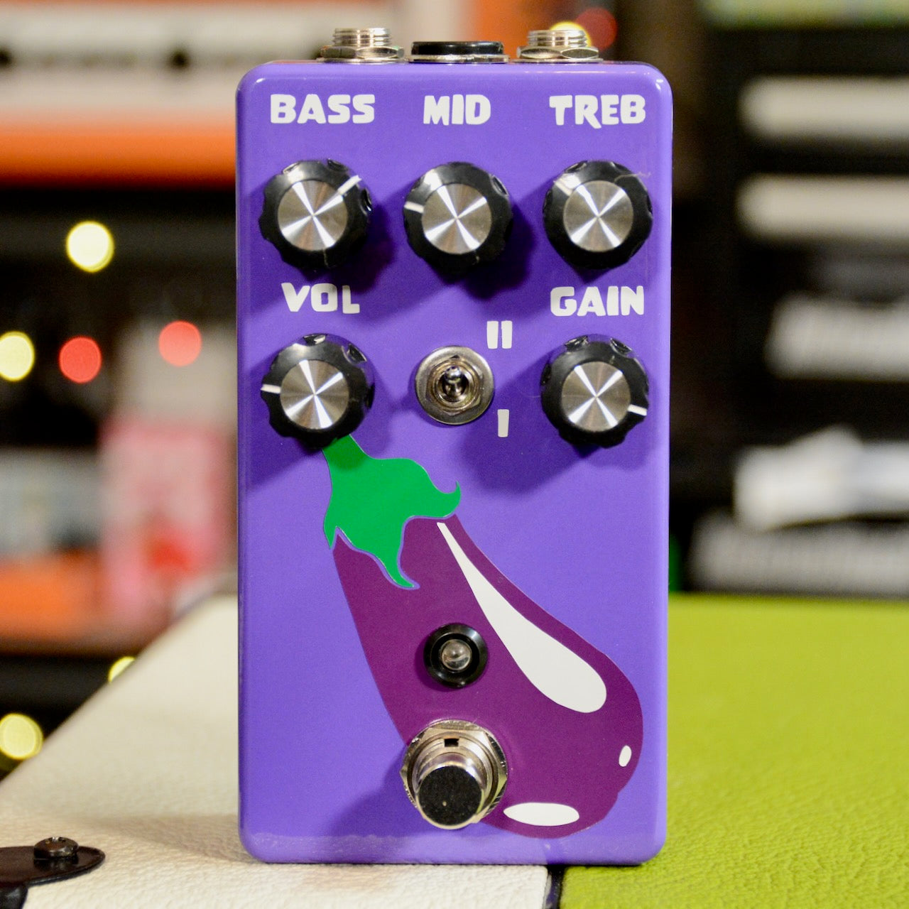 Purple distortion pedal with an eggplant graphic, six control knobs, a toggle switch, and a footswitch.