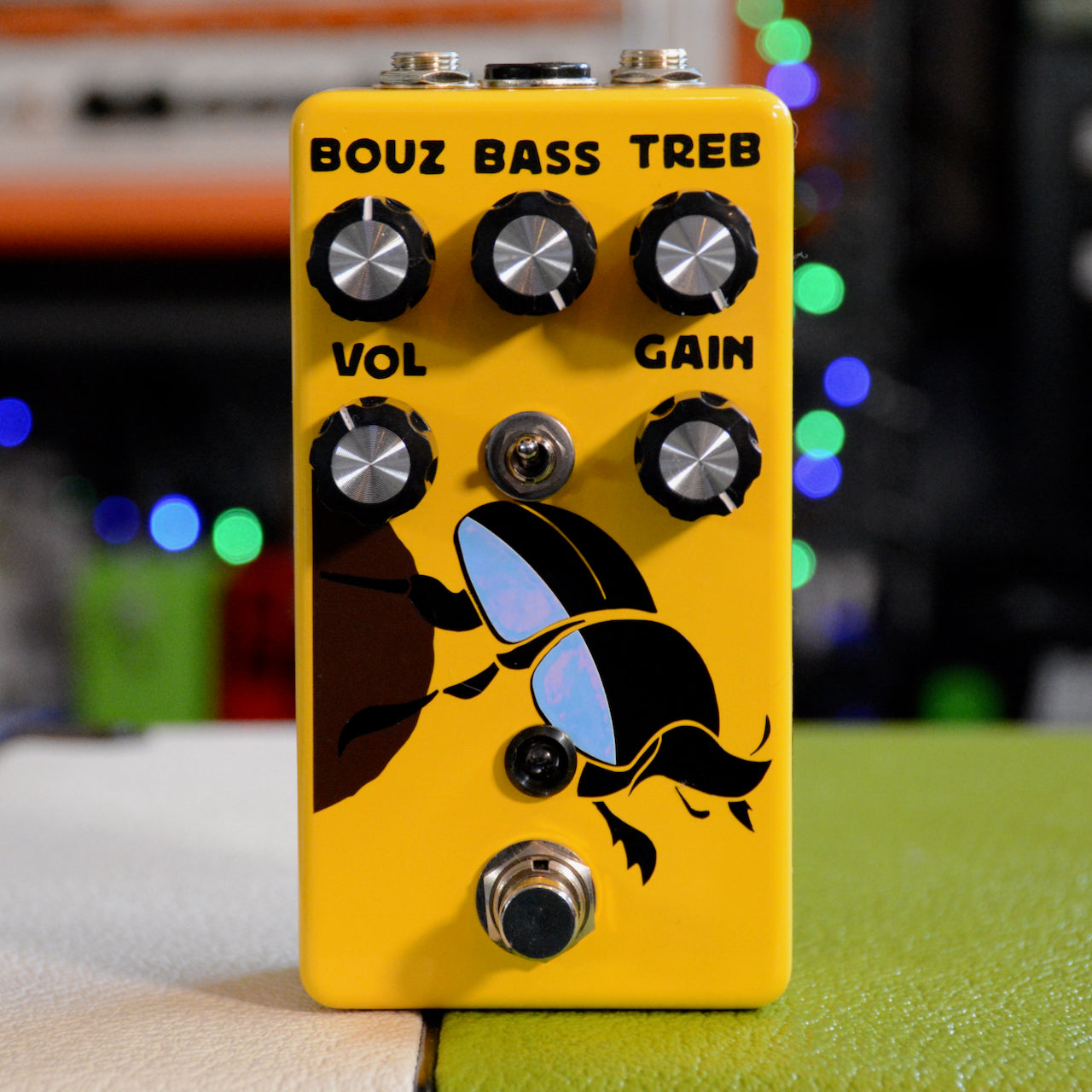 Yellow guitar effects pedal with four knobs, one toggle switch, one footswitch, and a silhouette of a beetle graphic.