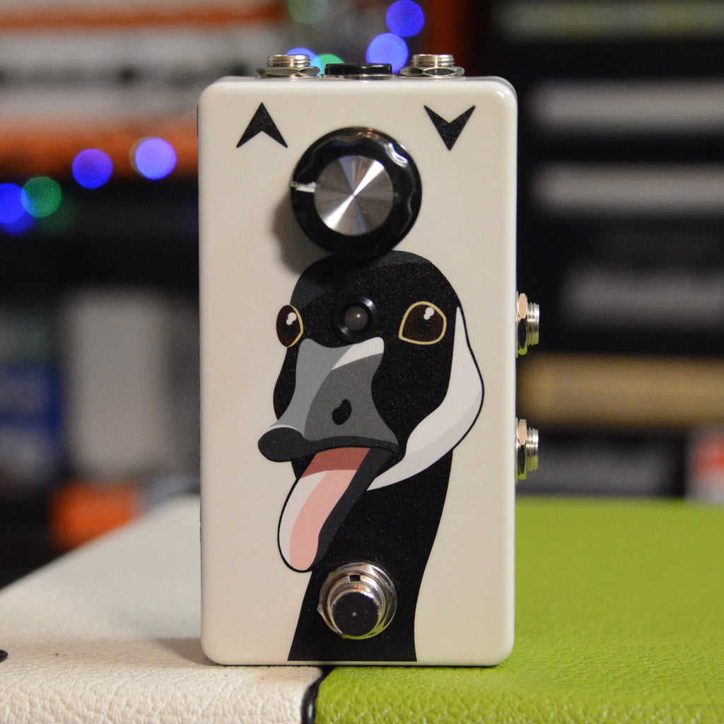 A white guitar effects pedal with a cartoon goose face, one rotary knob, and a footswitch.