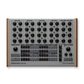 Top view of a grey and wooden edged electronic drum machine with multiple rotary knobs and illuminated buttons.