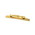 Gold-colored metal guitar bridge component viewed at slight angle on white background.