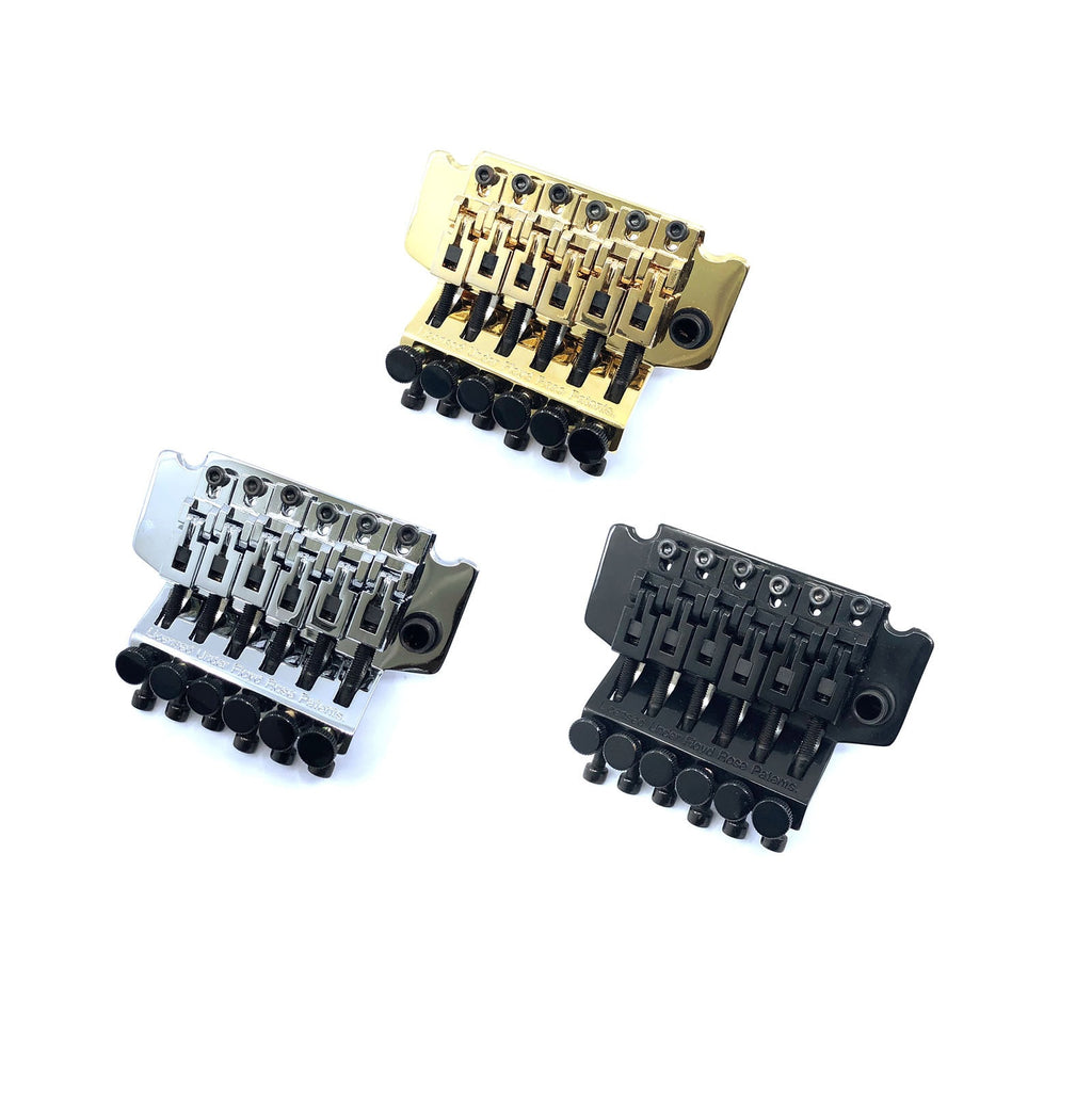 Three metallic guitar tremolo bridges in gold, silver, and black colors on a white background.