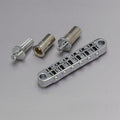 Silver-colored metal Tune-o-matic style guitar bridge with two threaded bushings and a bridge post on gray background.