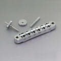Silver metal ABR-style guitar bridge with two screws and a thumbwheel nut on gray background.