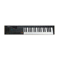 Black electronic keyboard synthesizer with keys, knobs, buttons, joystick, and small display screen.