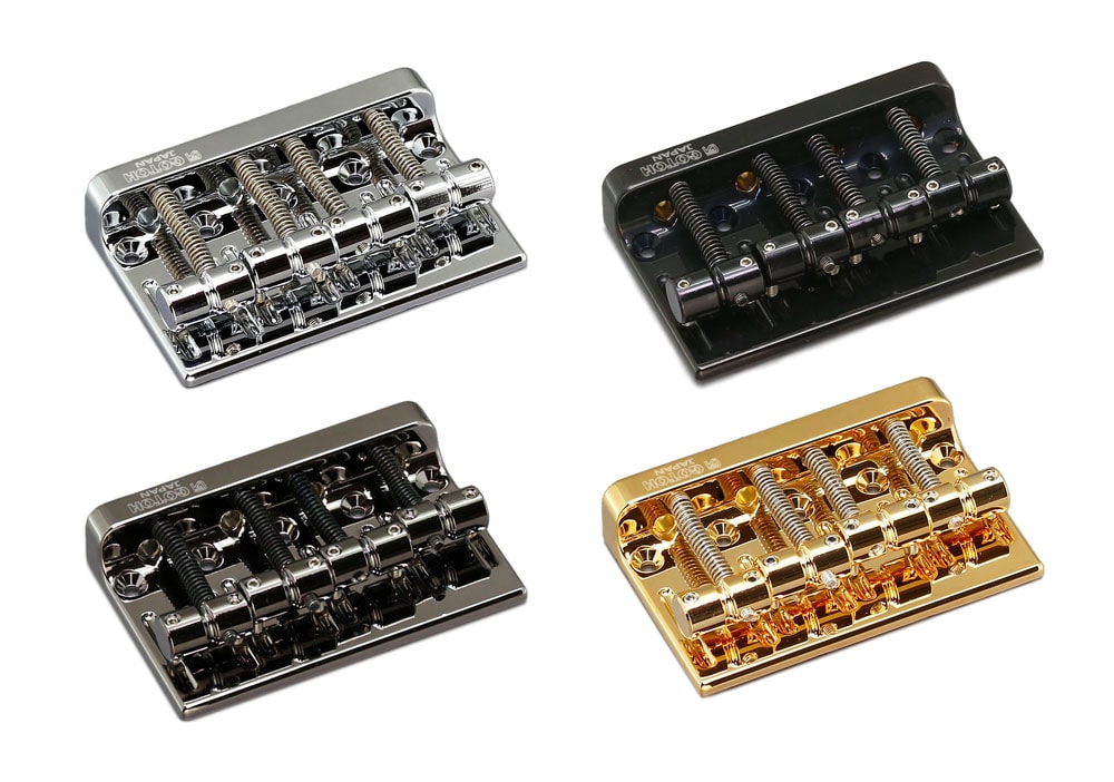 Four metal bass guitar bridges in silver, black, dark gray, and gold finish shown on white background.