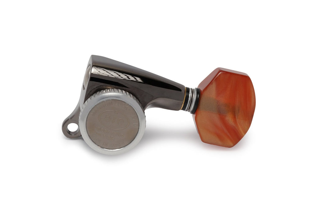 A single black and silver guitar tuning machine head with an orange tuning peg is shown on a white background.