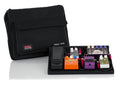 Black pedalboard with multiple effect pedals and a black carrying bag labeled Pedal Tote