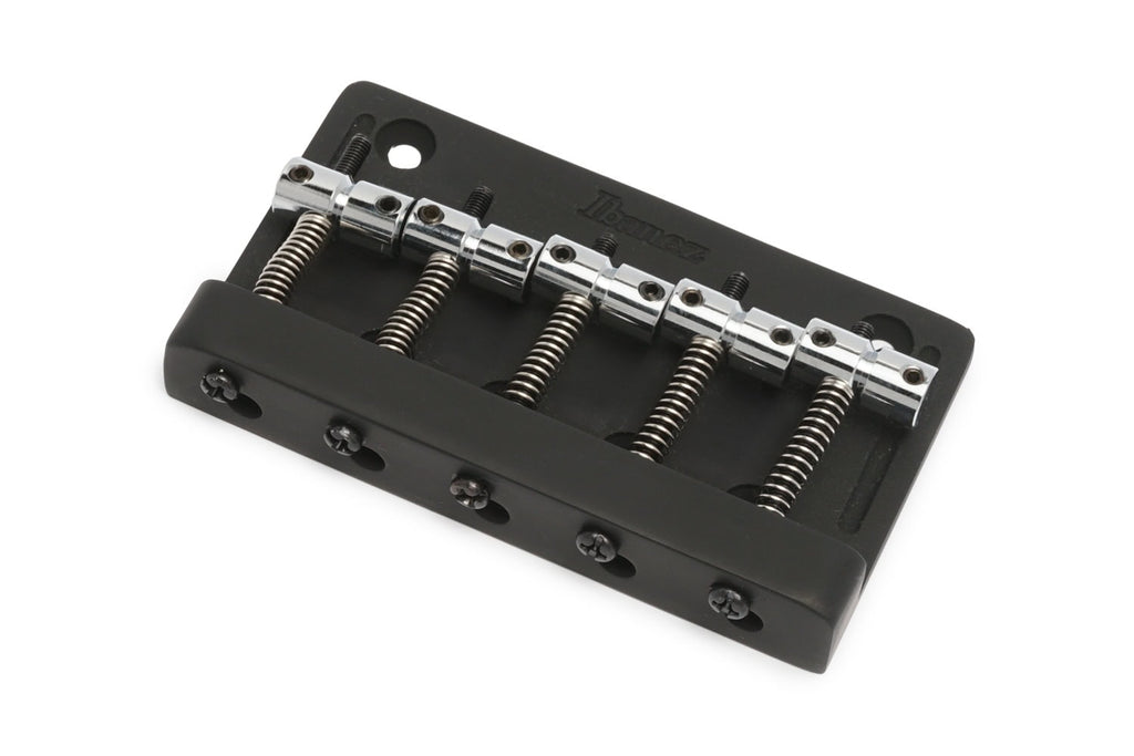 Black and silver metal guitar bridge component with five tuning saddles and springs on a white background.