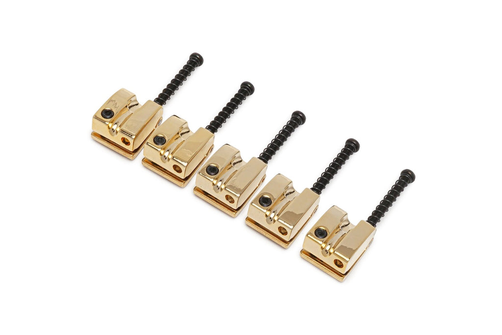 Five gold and black bass saddles with adjustment screws arranged in a row on a white background.