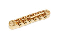 Gold-colored metal guitar bridge with six saddle adjustment screws and two mounting holes.