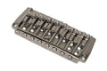 Close-up photo of a metallic 8-string guitar bridge with screws and adjustable saddles.