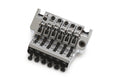 Close-up of six-string chrome tremolo bridge for guitar with individual string saddles and adjustment knobs.