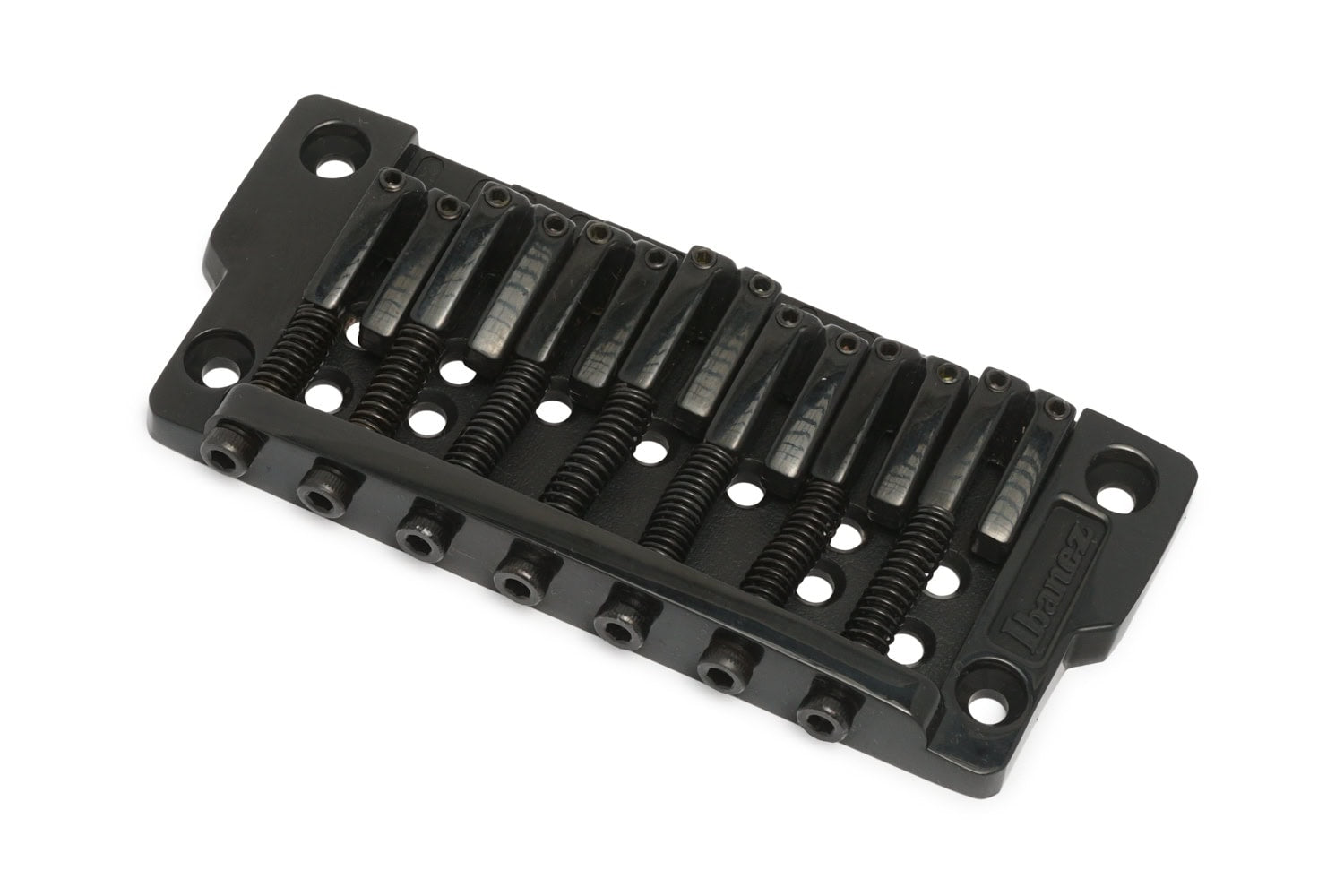 Black metal fixed guitar bridge with seven string saddles and screw adjustments.