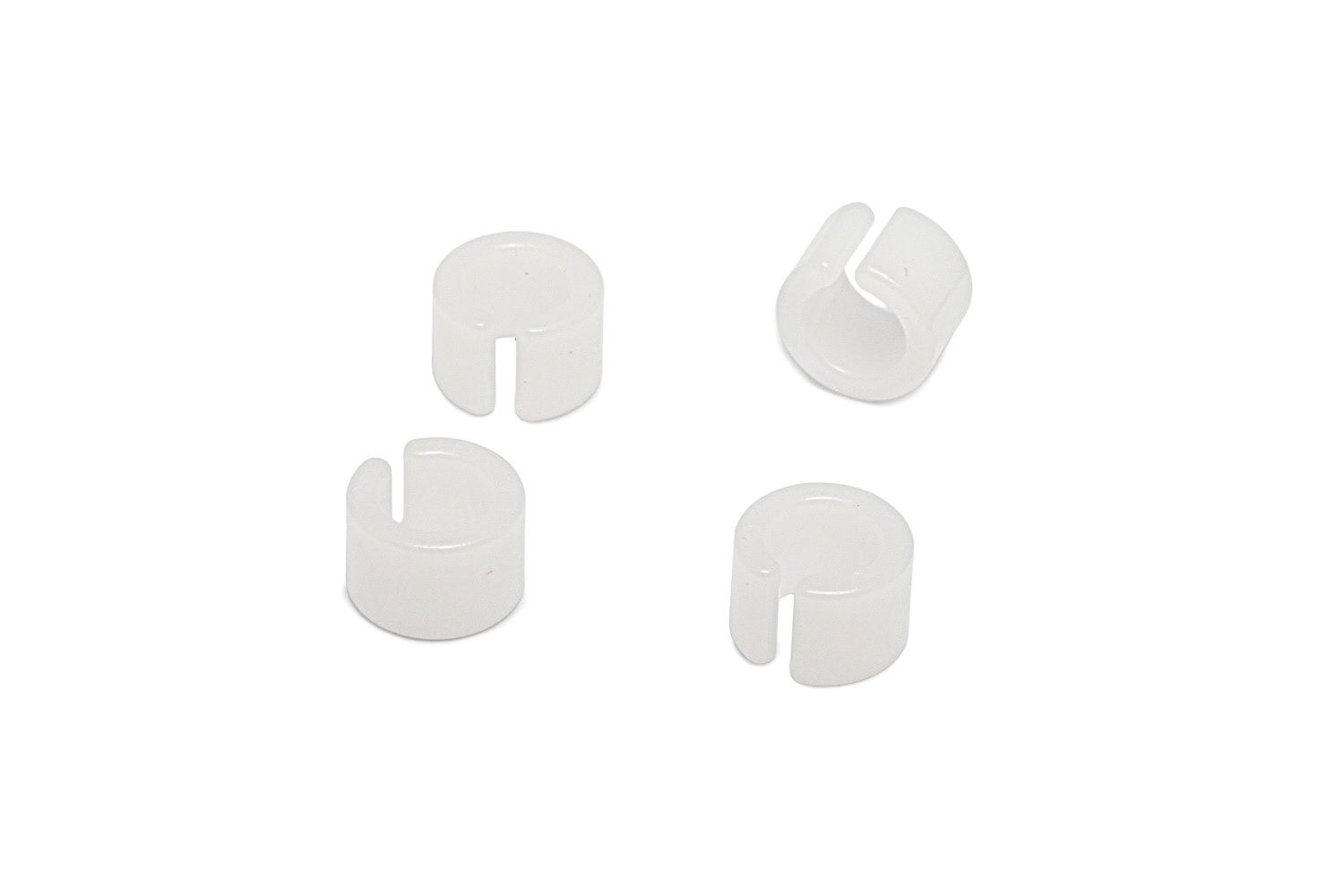 Four small white plastic split bushings arranged on a white background.