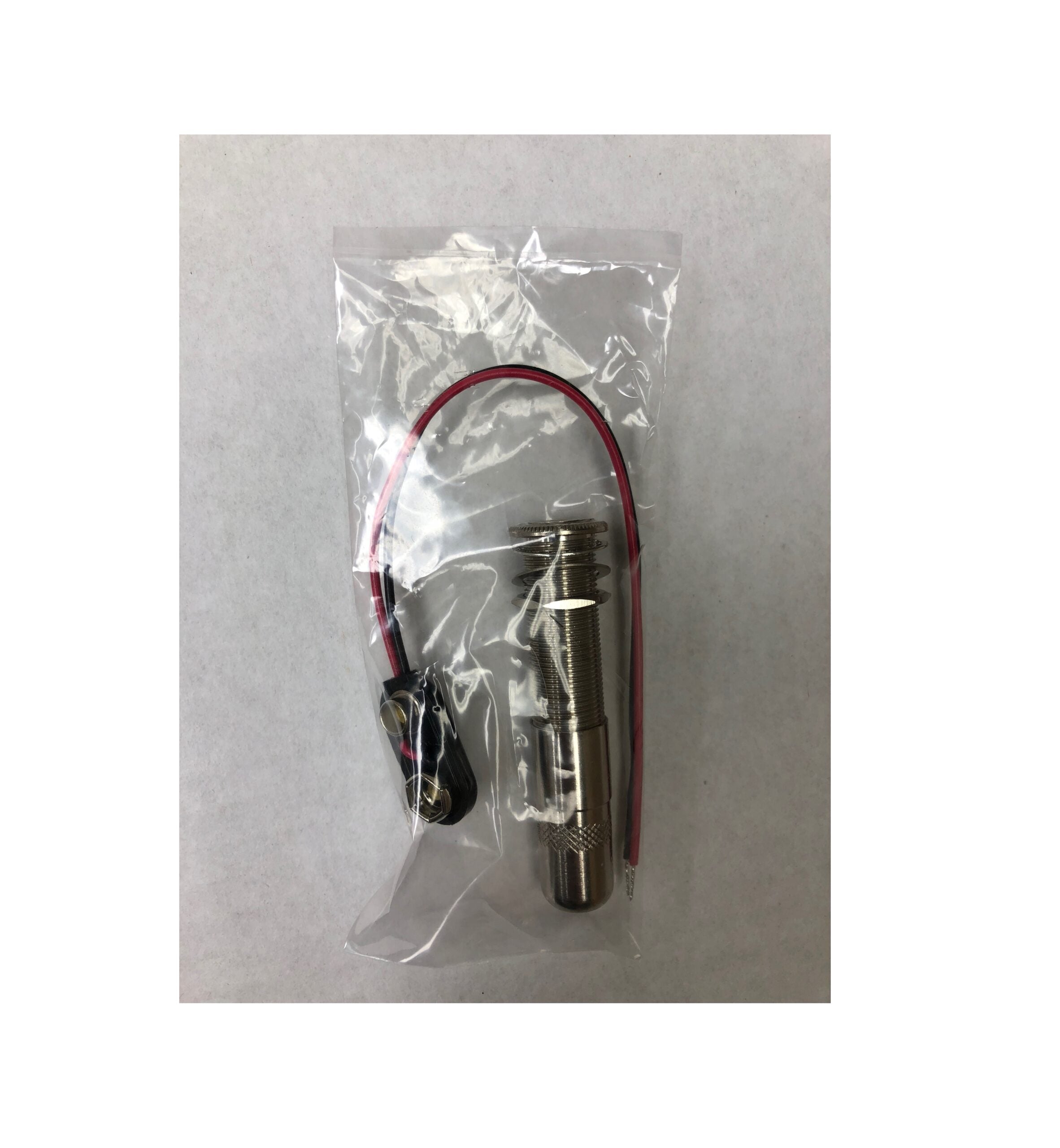 A packaged 1/4-inch stereo jack with threaded mount, washer, nut, and a 9V battery clip with attached wires.