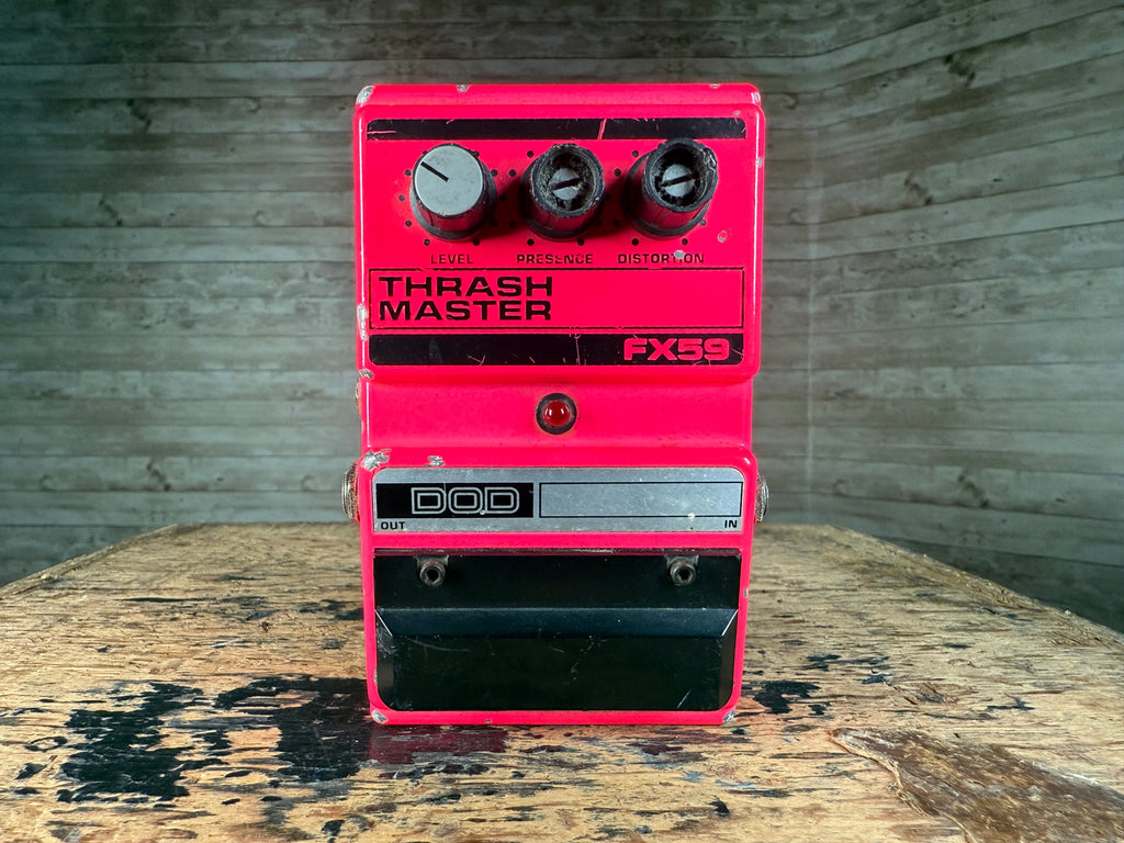 Red DOD Thrash Master FX59 guitar effects pedal with three control knobs on a wooden surface.