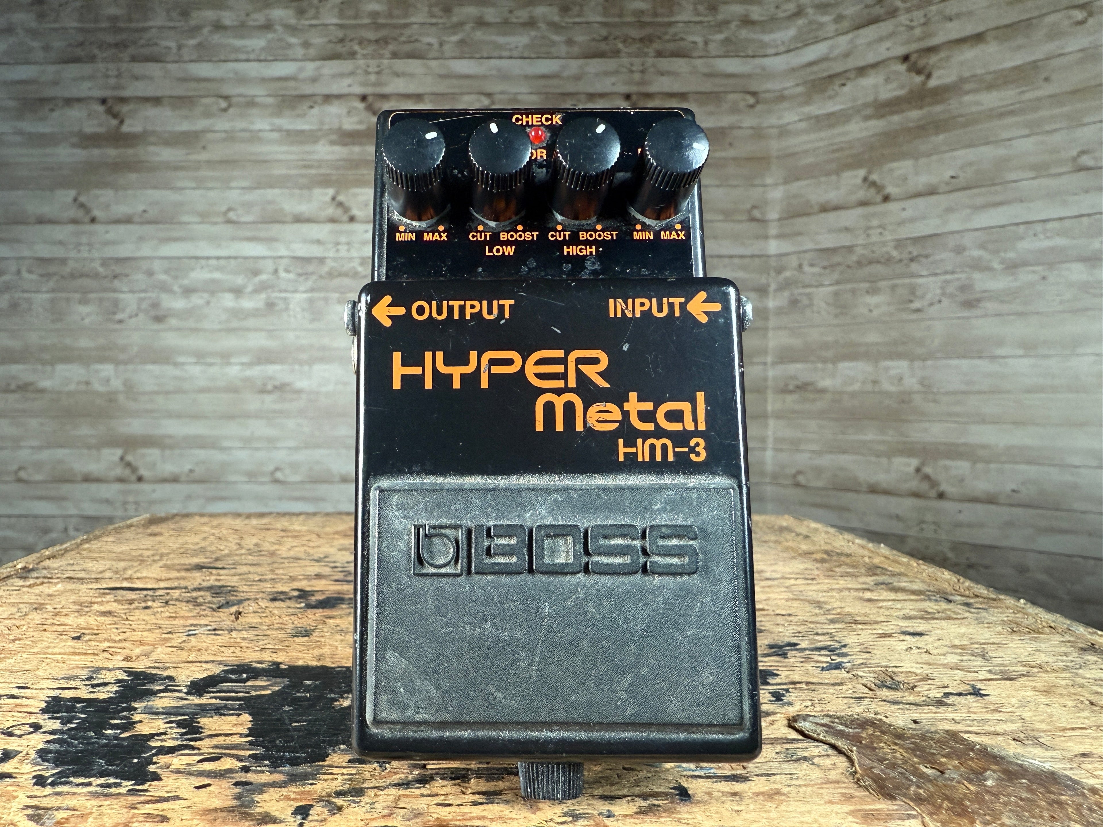 Black guitar distortion pedal with four knobs and orange text labeled Hyper Metal HM-3 by Boss.