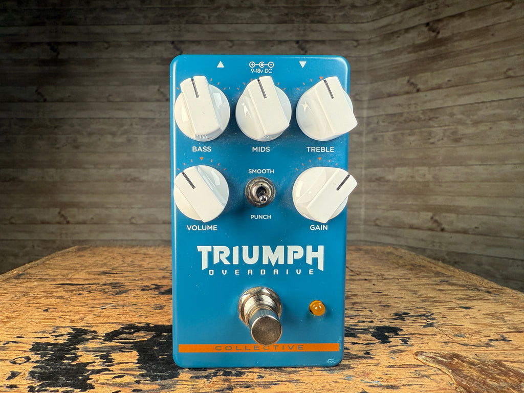 Blue guitar effects pedal with white knobs labeled bass, mids, treble, volume, gain, and a toggle switch labeled smooth punch.