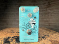 Light blue guitar effects pedal with three knobs, one toggle switch, one footswitch, and a bear riding a bicycle illustration.