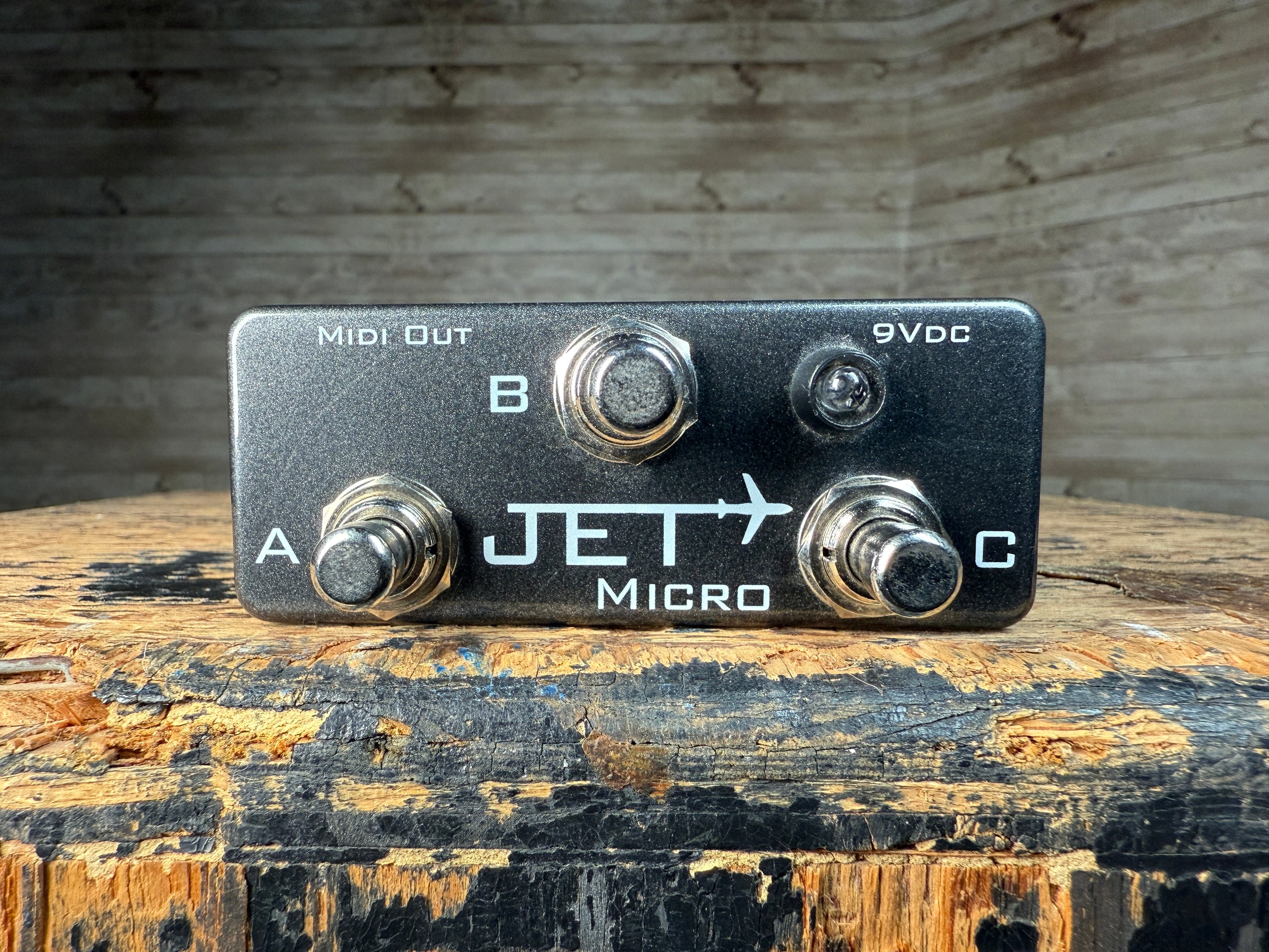 Black metal pedal with three footswitches and MIDI Out and power jacks, labeled Jet Micro.
