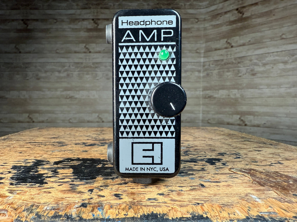 Black and white Electro-Harmonix headphone amplifier pedal with one rotary knob and two jacks visible on the sides.