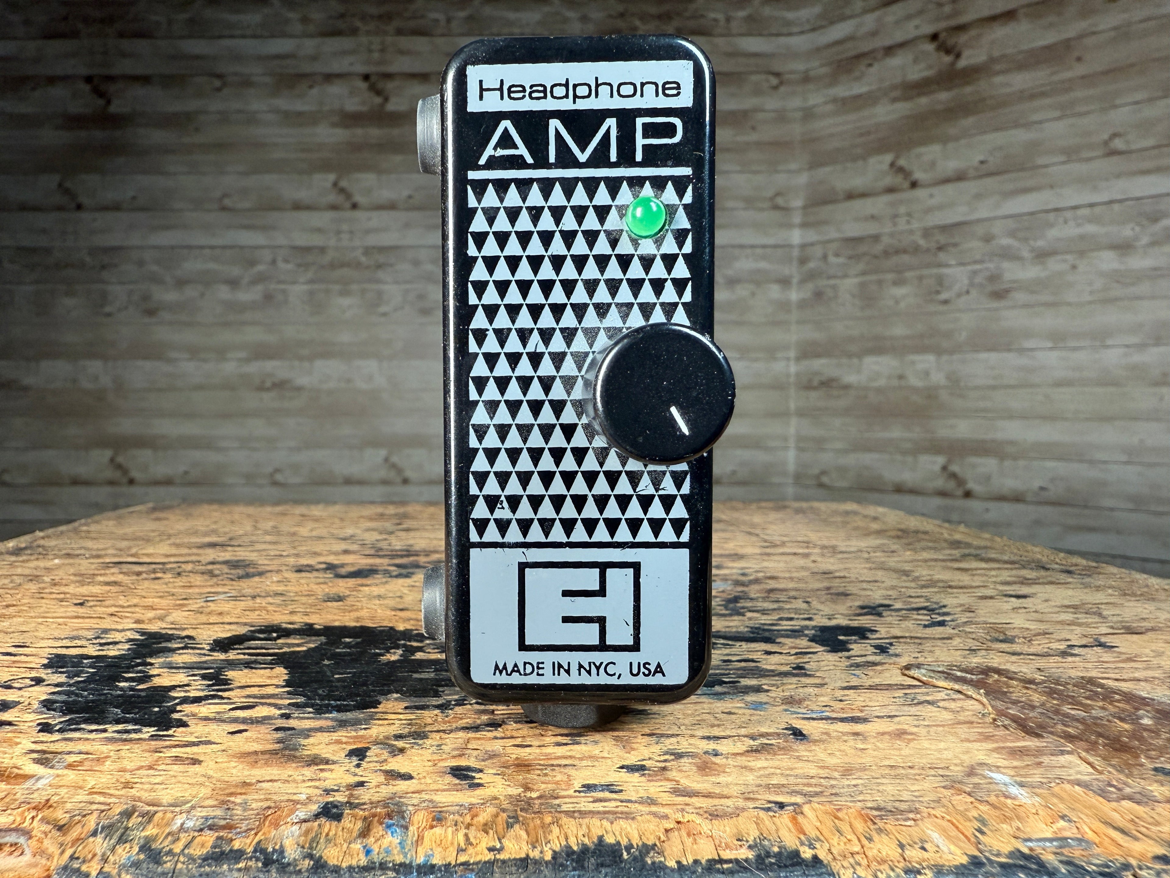 Black and white Electro-Harmonix headphone amplifier pedal with one rotary knob and two jacks visible on the sides.