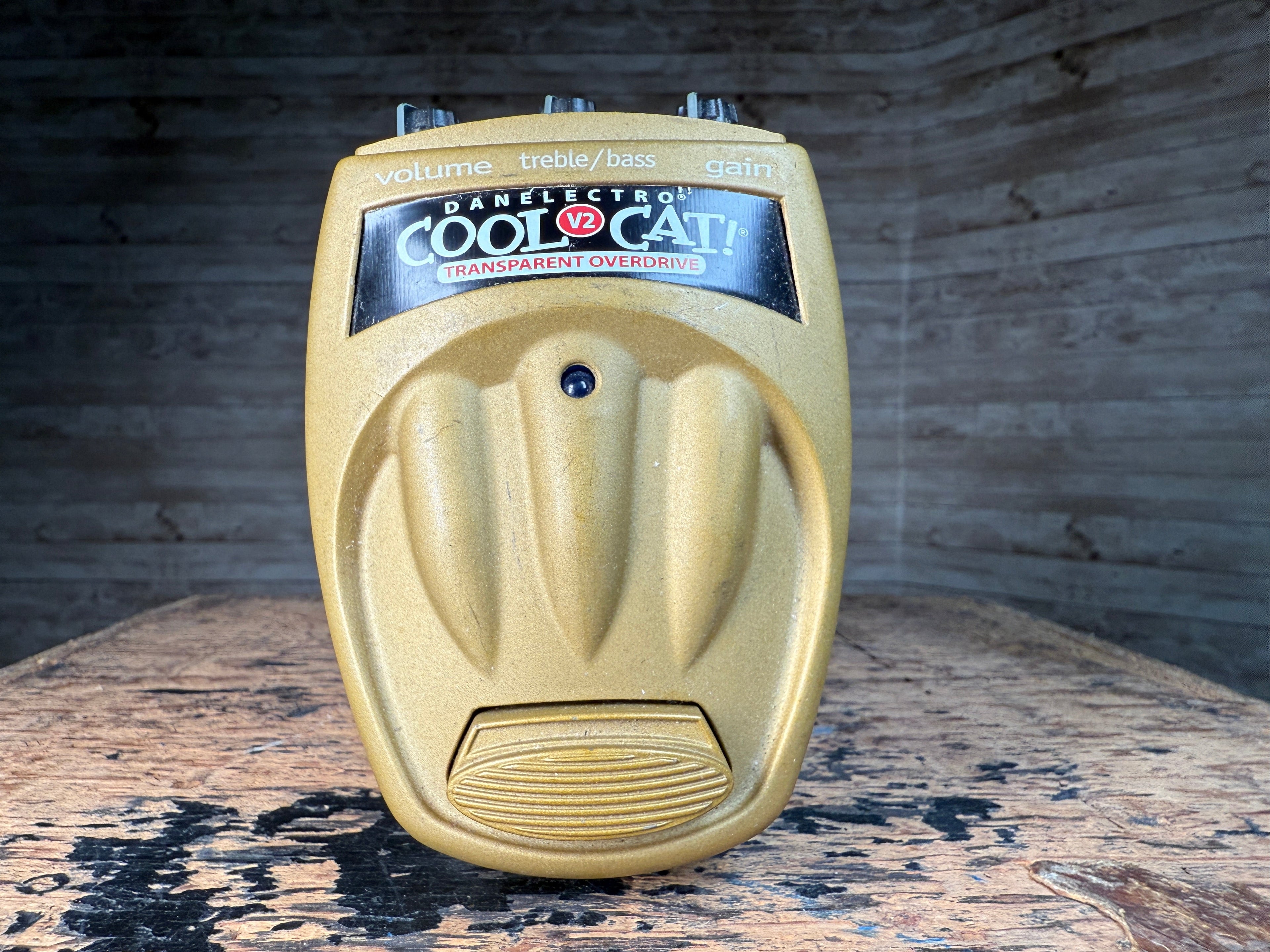 Golden guitar effects pedal with three control knobs and a footswitch labeled Cool Cat V2 Transparent Overdrive.