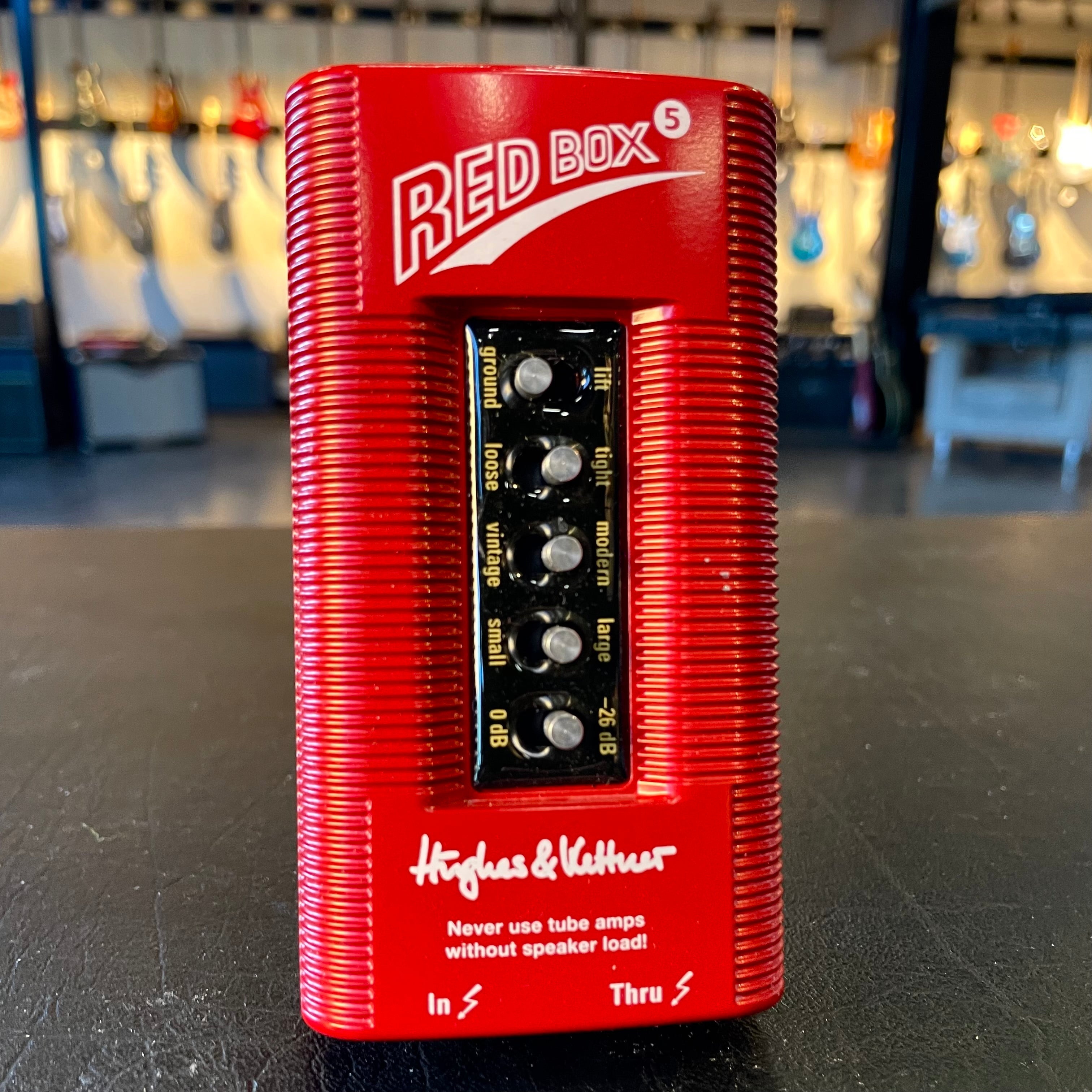 Red Hughes & Kettner pedal with five control knobs and input/thru jacks on the front, on a black surface.