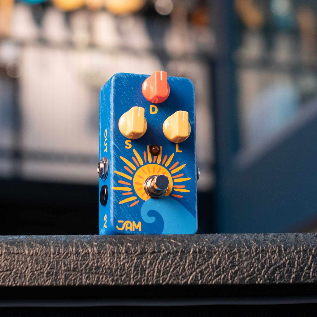 Blue guitar effects pedal with orange and yellow sun design and three control knobs labeled S, D, and L with a foot switch and visible input/output jacks.