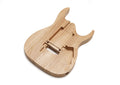 Natural ash wood electric guitar body with routed cavities, viewed at an angled perspective on a white background.