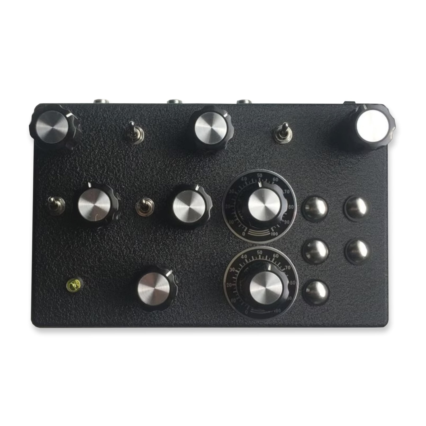 Black rectangular device with multiple silver knobs, toggle switches, and push buttons on its surface.