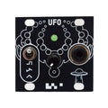 Small black electronic module with a toggle switch, rotary knob, audio jack, green LED, and UFO graphic.