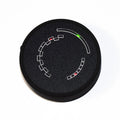 Round black tuner device with geometric dial markings and red and green LED indicators on front face.