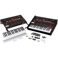 Two synthesizer modules with keyboards, control panels, and mounting hardware laid out on a white surface.