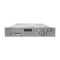 Front view of a gray rackmount digital sampler with buttons, screen, knobs, and audio jacks.